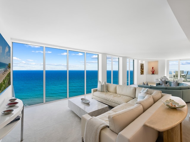 living room featuring carpet flooring, a water view, and a wall of windows