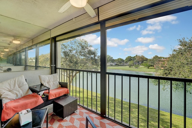 sunroom with ceiling fan and a water view