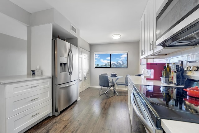 kitchen with decorative backsplash, white cabinetry, stainless steel appliances, and dark hardwood / wood-style floors