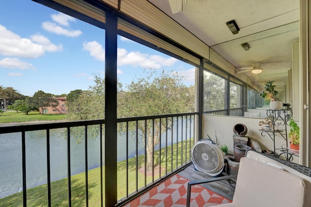 sunroom / solarium featuring ceiling fan and a water view