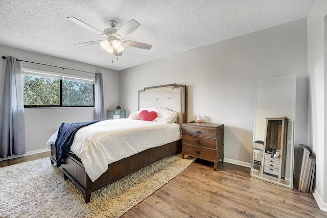 bedroom featuring wood-type flooring, a textured ceiling, and ceiling fan