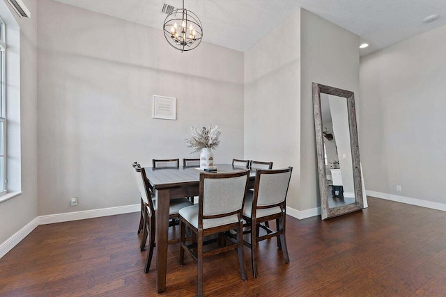 dining area with dark wood-type flooring, a chandelier, and a textured ceiling