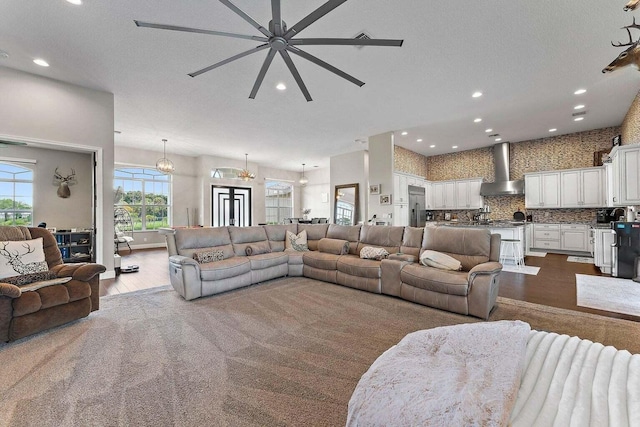 living room featuring ceiling fan with notable chandelier, hardwood / wood-style floors, and a textured ceiling