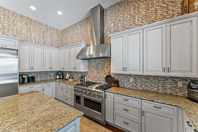 kitchen featuring white cabinetry, wall chimney exhaust hood, high quality appliances, and stone countertops