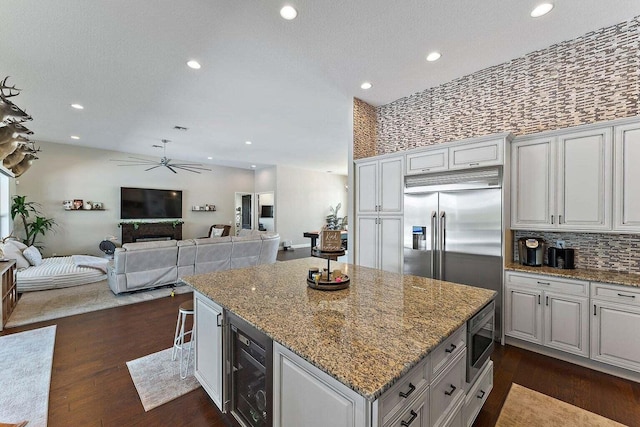 kitchen featuring light stone counters, white cabinets, dark wood-type flooring, beverage cooler, and stainless steel microwave