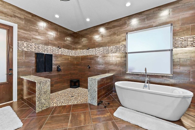 bathroom featuring tile patterned flooring, a bathing tub, and tile walls