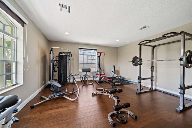 exercise area with dark wood-type flooring and a textured ceiling