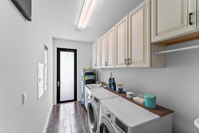 clothes washing area featuring cabinets, water heater, a textured ceiling, sink, and washing machine and clothes dryer