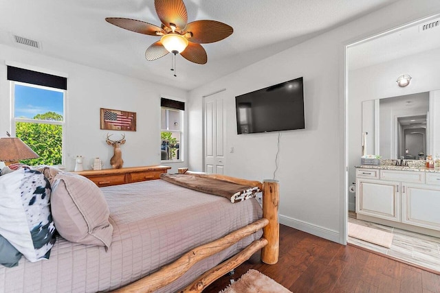 bedroom featuring a closet, dark hardwood / wood-style floors, sink, ceiling fan, and ensuite bathroom