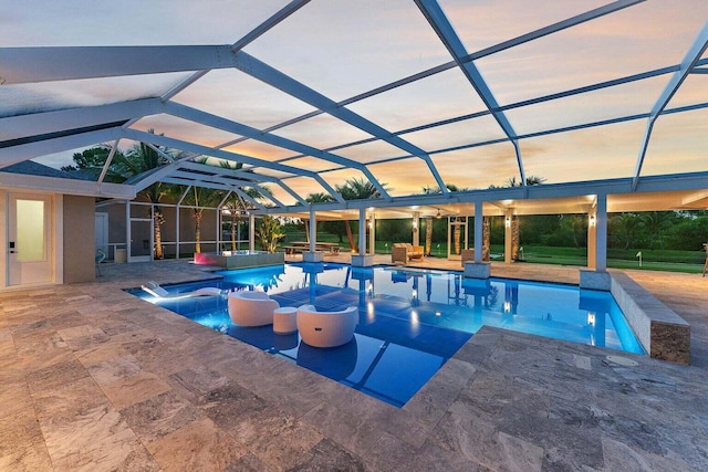 pool at dusk featuring a patio and glass enclosure