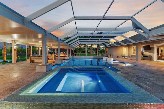 pool at dusk with a lanai and a patio