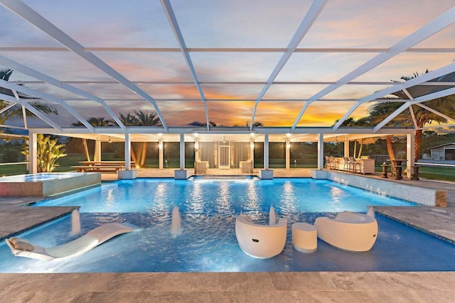 pool at dusk featuring glass enclosure, a patio area, and pool water feature