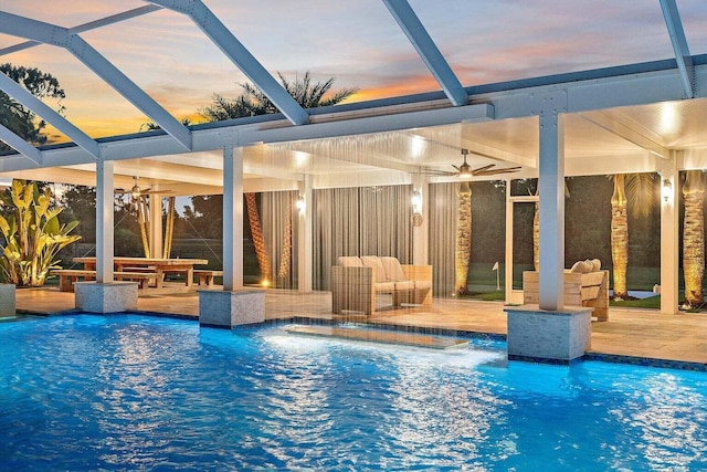 pool at dusk featuring a patio, a lanai, and ceiling fan