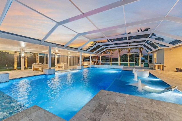 pool at dusk with glass enclosure, pool water feature, and a patio area