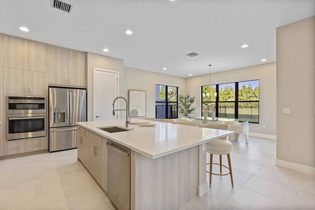 kitchen featuring light brown cabinets, appliances with stainless steel finishes, sink, and a kitchen island with sink