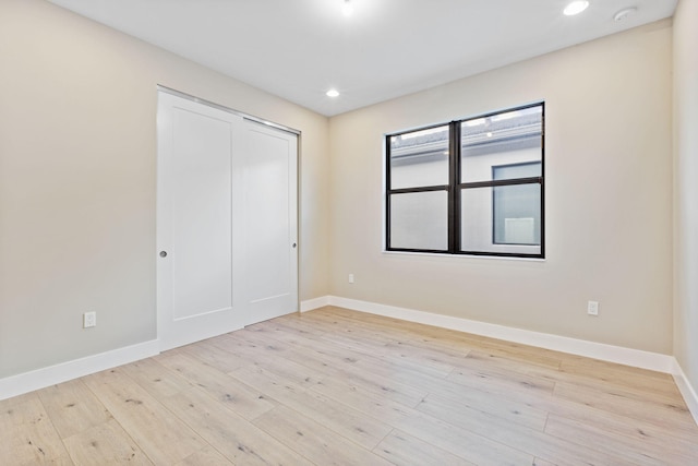 unfurnished bedroom featuring light wood-type flooring and a closet