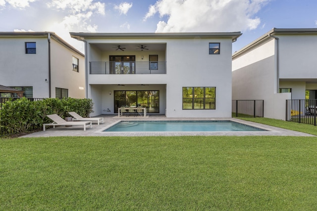 back of property with a fenced in pool, a patio, a yard, and ceiling fan