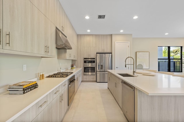 kitchen featuring light brown cabinets, stainless steel appliances, sink, and an island with sink