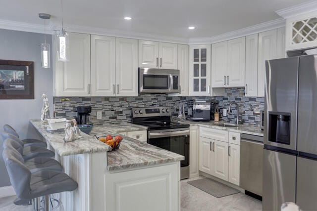 kitchen featuring white cabinetry, sink, light stone counters, kitchen peninsula, and appliances with stainless steel finishes