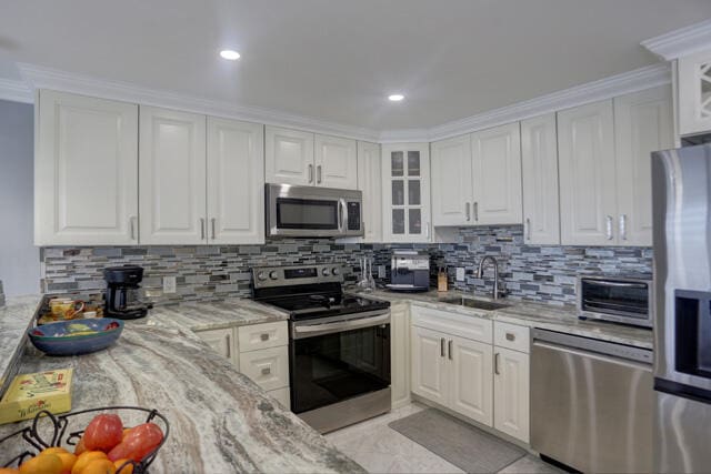 kitchen with sink, white cabinets, ornamental molding, and appliances with stainless steel finishes