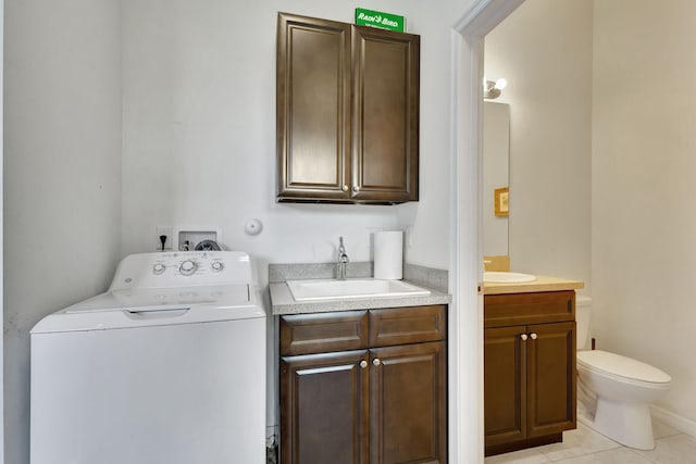 washroom featuring light tile patterned flooring, washer / clothes dryer, cabinets, and sink