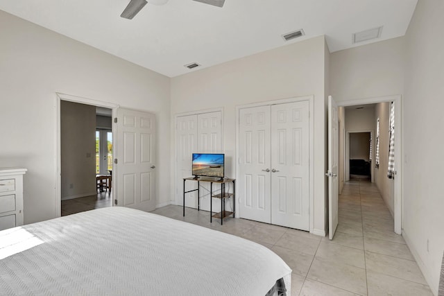 bedroom with multiple closets, ceiling fan, and light tile patterned floors