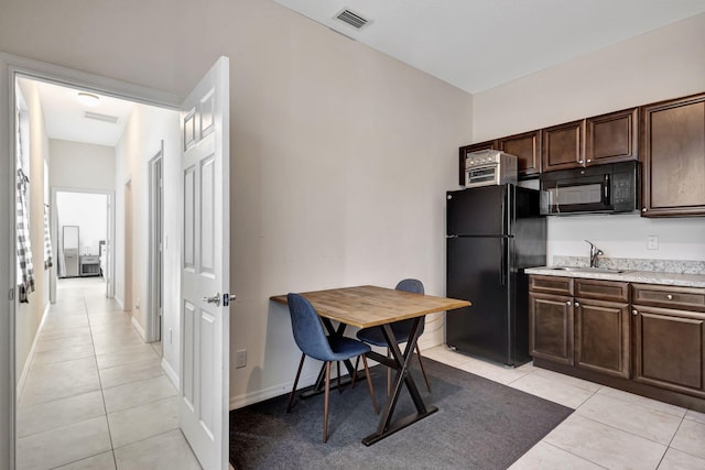 kitchen with dark brown cabinets, sink, light tile patterned floors, and black appliances