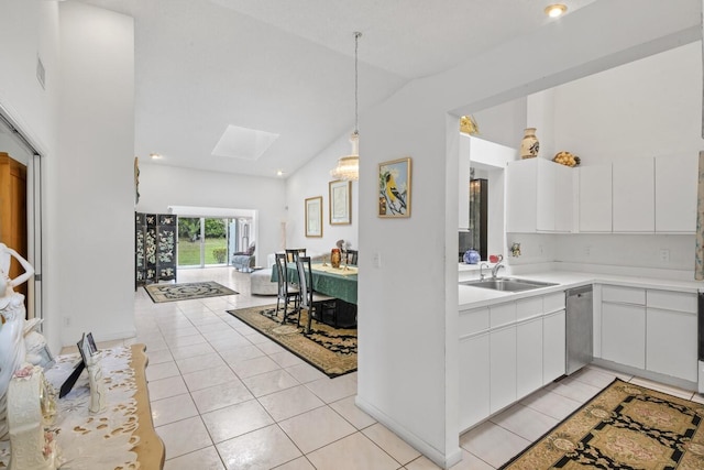 kitchen featuring sink, hanging light fixtures, vaulted ceiling with skylight, stainless steel dishwasher, and white cabinetry