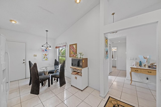 dining room with a notable chandelier, light tile patterned floors, and high vaulted ceiling