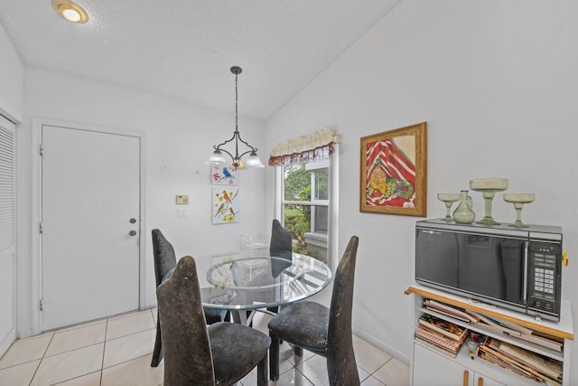 dining area featuring a notable chandelier, lofted ceiling, a textured ceiling, and light tile patterned floors