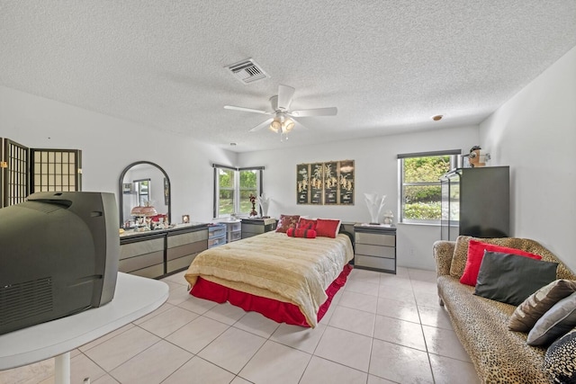 bedroom with ceiling fan, light tile patterned floors, a textured ceiling, and multiple windows