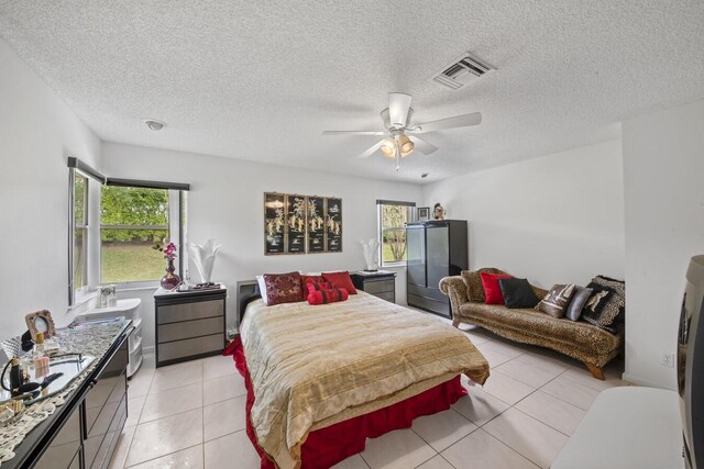 tiled bedroom with ceiling fan and a textured ceiling