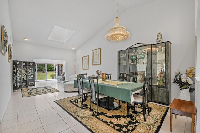 dining space with a skylight, an inviting chandelier, light tile patterned flooring, and high vaulted ceiling