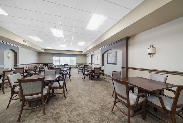 carpeted dining room with a drop ceiling