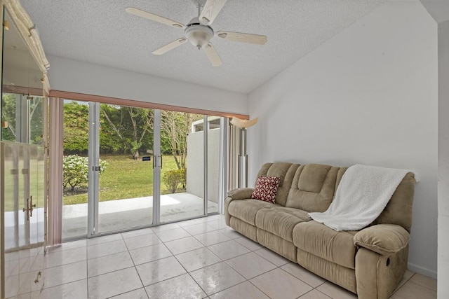 living room with ceiling fan, light tile patterned floors, and a textured ceiling