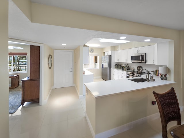 kitchen with light tile patterned flooring, sink, white cabinets, kitchen peninsula, and stainless steel appliances