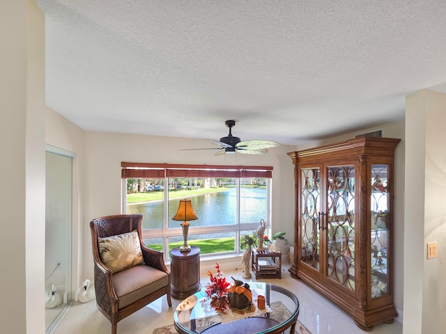 sitting room with light tile patterned flooring, a textured ceiling, and a water view