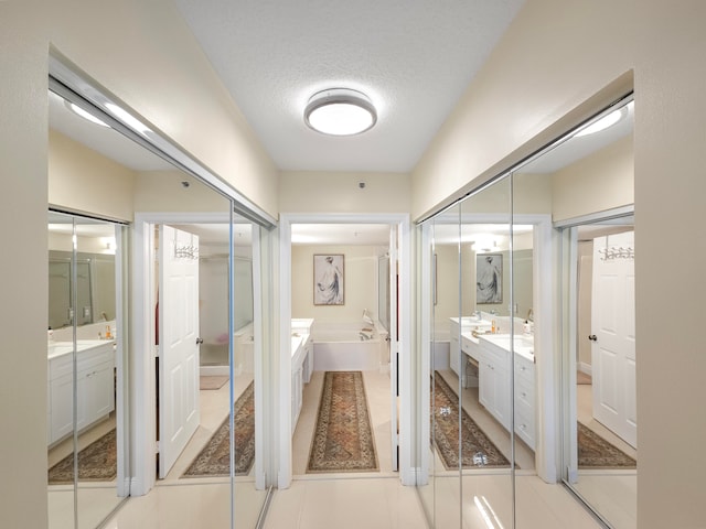 bathroom featuring vanity, tile patterned flooring, a washtub, and a textured ceiling