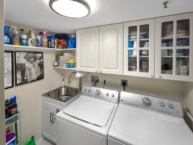 laundry room featuring cabinets, sink, separate washer and dryer, and a textured ceiling