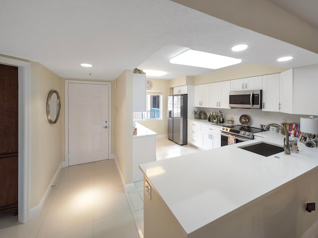 kitchen with light tile patterned flooring, white cabinetry, sink, kitchen peninsula, and appliances with stainless steel finishes