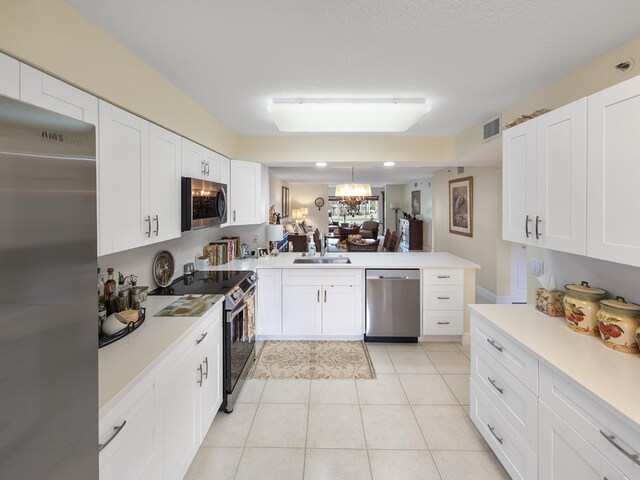 kitchen with kitchen peninsula, appliances with stainless steel finishes, sink, and white cabinets