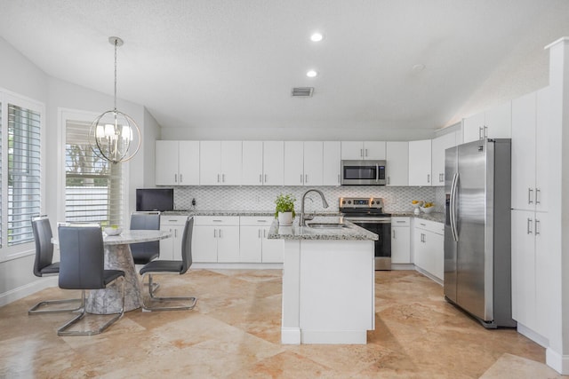 kitchen featuring white cabinets, appliances with stainless steel finishes, a kitchen island with sink, and sink