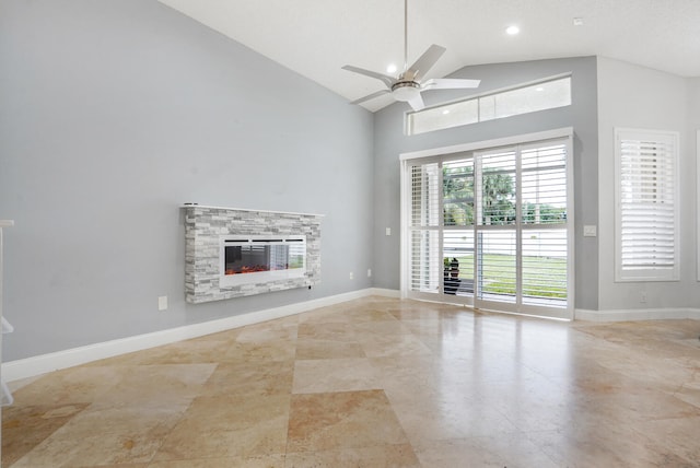 unfurnished living room with a stone fireplace, ceiling fan, and high vaulted ceiling