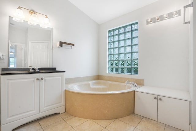 bathroom with tile patterned flooring, vanity, a tub to relax in, and lofted ceiling