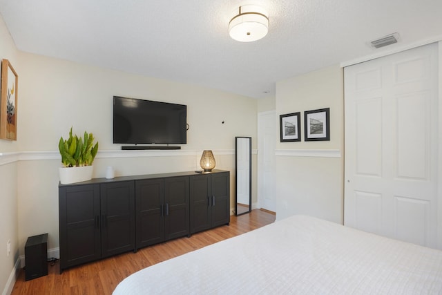 bedroom with a closet, light hardwood / wood-style flooring, and a textured ceiling