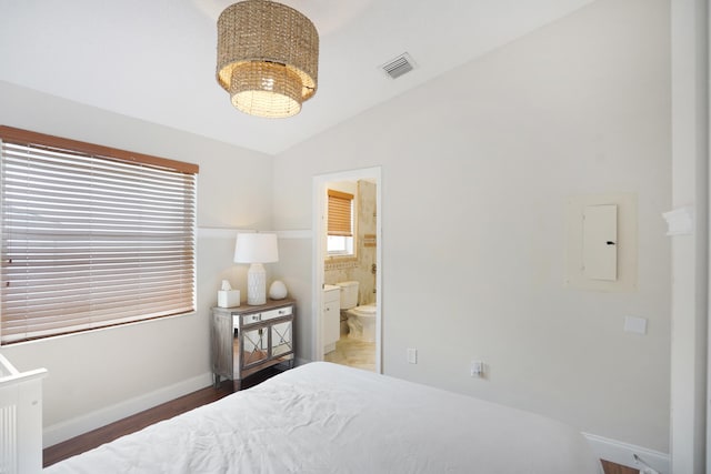 bedroom featuring connected bathroom, multiple windows, dark wood-type flooring, and lofted ceiling