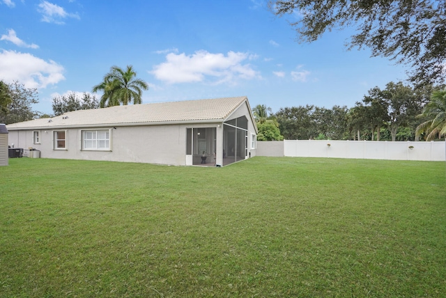 rear view of house featuring a yard and a sunroom