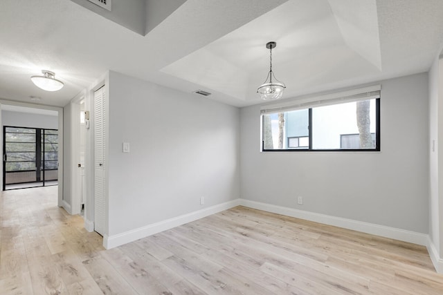 empty room with light hardwood / wood-style floors and an inviting chandelier