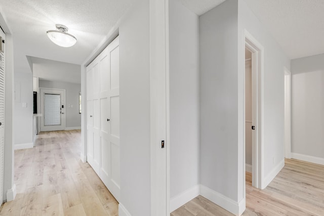 hallway featuring light wood-type flooring and a textured ceiling