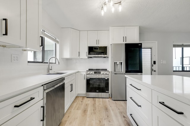 kitchen with plenty of natural light, white cabinetry, sink, and appliances with stainless steel finishes